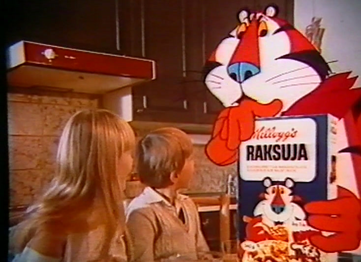 In the kitchen, Tony the Tiger stands with a large pack while children eat.