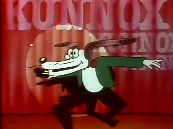 The dog in the green jacket runs across the stage, tie flying.
