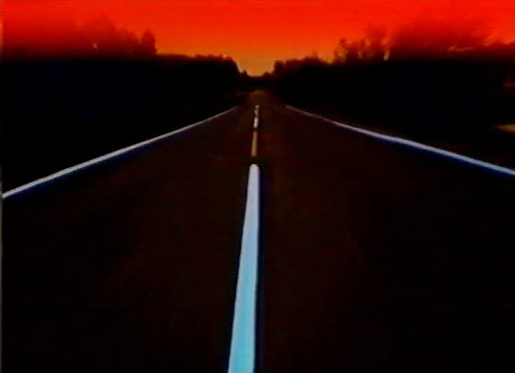 A dark road with a glowing white centre line under a thin red horizon band.