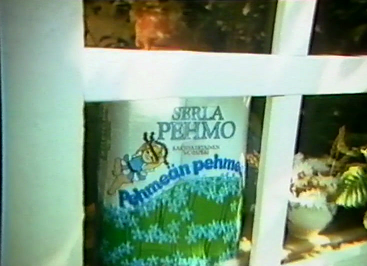 A roll of Serla Pehmo on an outhouse window ledge behind a white frame.