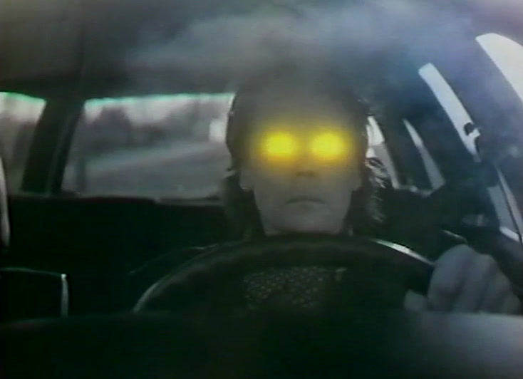 A driver at the wheel with glowing yellow eyes in a misty cabin.
