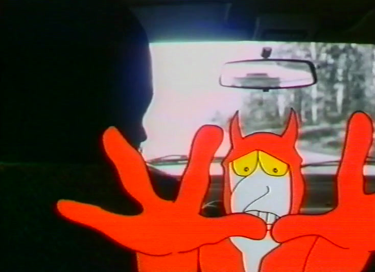 A red cartoon devil spreads both hands wide across the car's dashboard.