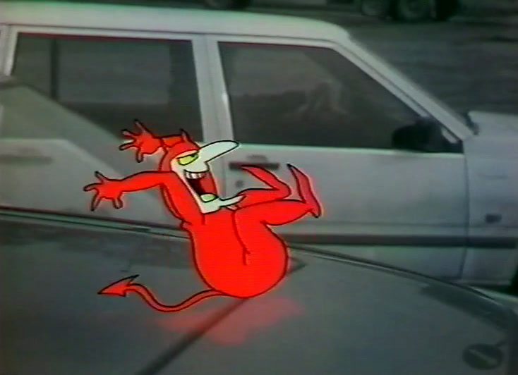 The red devil dances on a car bonnet in front of a white van.
