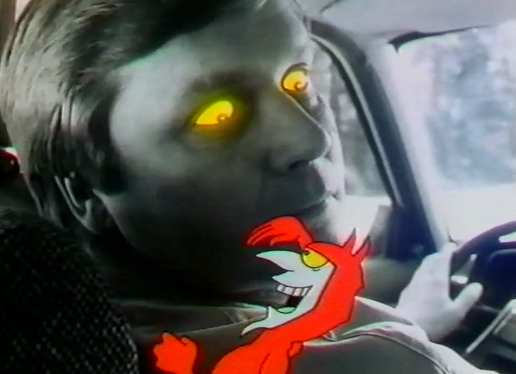The red devil grins beside the yellow-eyed driver at the steering wheel.