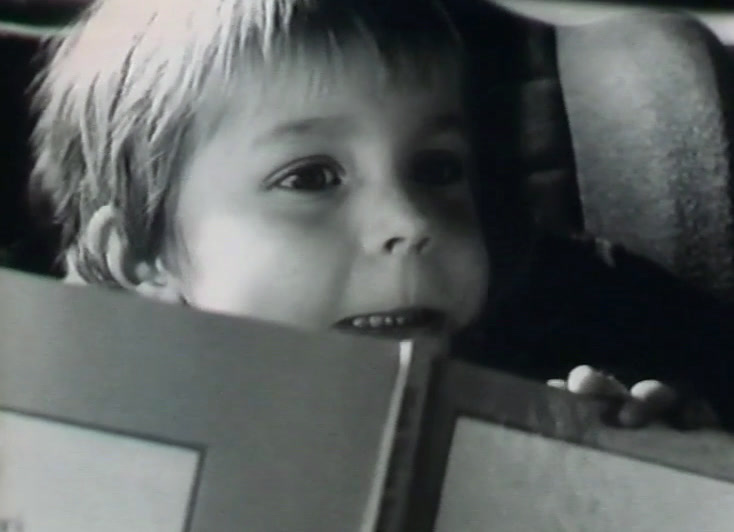 A young child's face in close-up beside the edge of a board.