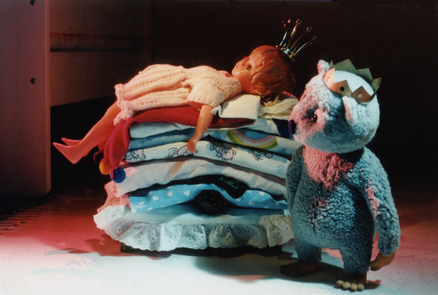 Still from Urpo and Turpo — Urpo beside a stack of folded laundry that has become the princess's mattresses